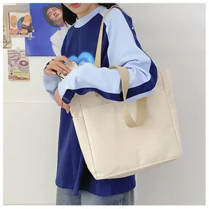Détail d'un grand sac fourre-tout en toile avec sangles contrastées et poche frontale large