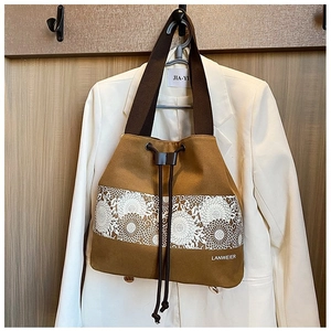 Close-up of brown canvas bucket bag with white floral embroidery and drawstring closure