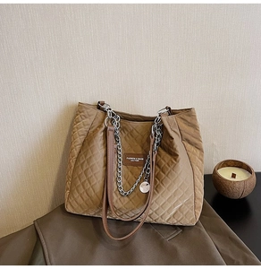 Détail du sac cabas matelassé marron montrant le patch en cuir et la bandoulière chaîne