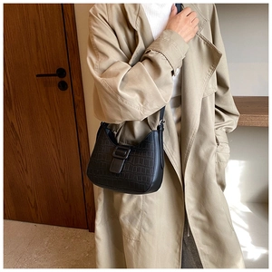 Close-up of black crocodile pattern faux leather shoulder bag with square buckle detail
