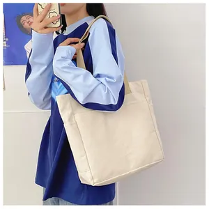 Détail du cabas en toile blanc cassé avec poche avant et sangle marron pour le quotidien