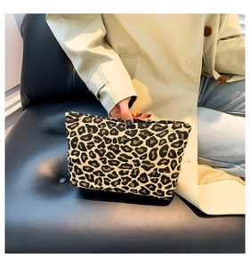 Close-up of stylish leopard print clutch bag held by model with elegant beige trench coat