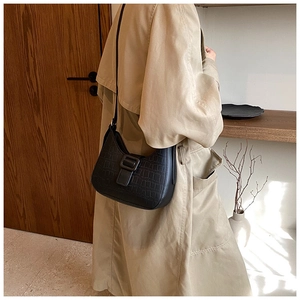 Detailed view of black crocodile pattern faux leather shoulder bag with a large front buckle