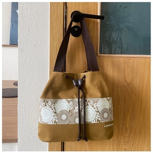 Detailed close-up of ginger yellow canvas bucket bag featuring floral pattern embroidery