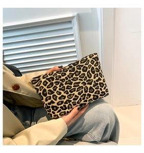 Detail of trendy leopard print clutch bag with textured fabric held by a model