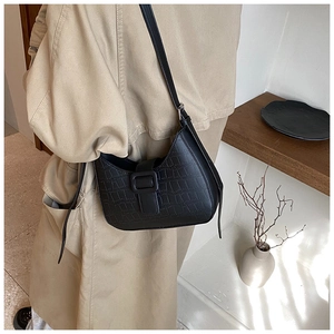 Detail of black crescent shoulder bag featuring premium crocodile texture and large buckle
