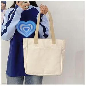 Détail d'un grand sac cabas en toile crème avec des anses kaki et une poche frontale