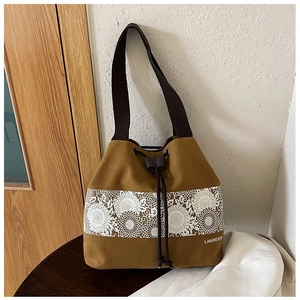 Detail of yellow canvas bucket bag featuring floral lace print and brown drawstring closure