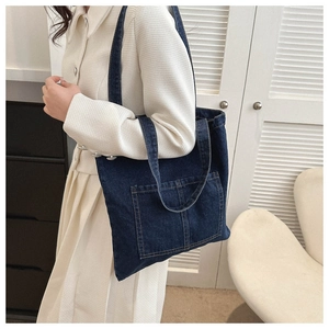 Detail of dark blue denim tote bag with visible double pockets and contrast stitching