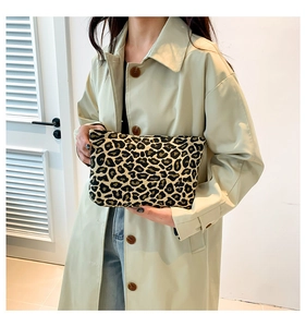 Detailed close-up of a trendy leopard print clutch bag paired with a beige trench coat