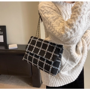 Gros plan du sac bandoulière en tweed noir et bleu avec une bandoulière chaîne