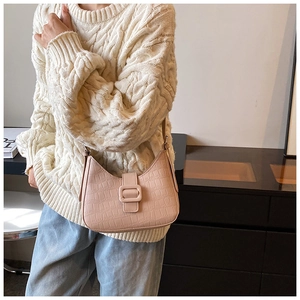 Detail of pink crocodile embossed shoulder bag styled with a warm knit sweater