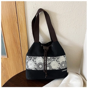 Detail of black canvas bucket bag featuring ethnic floral print and brown drawstring