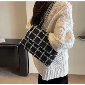 Détail du sac à bandoulière en tweed noir classique avec élégante bandoulière dorée