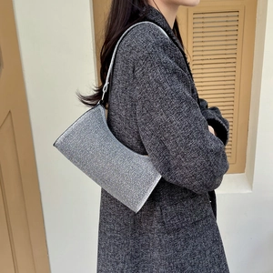 Schicke silberne Pailletten-Schultertasche am Modell mit dunklem Wollmantel getragen