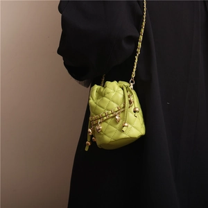 Lime green quilted bucket bag with gold heart charms and chain strap on a model
