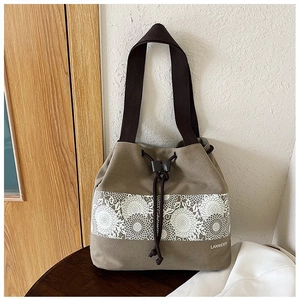 Detail view of khaki canvas drawstring bucket bag with sunflower print and woven handles