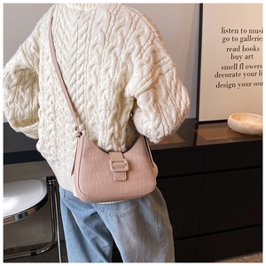 Detail showing pink crocodile embossed leather bag with square buckle on a model