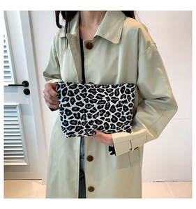 Chic leopard print fabric clutch bag held by a model in a minimalist stylish setting
