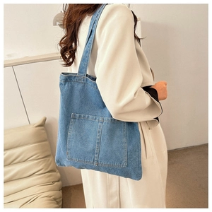 Detail view of light blue denim tote bag showing side texture and wide shoulder strap