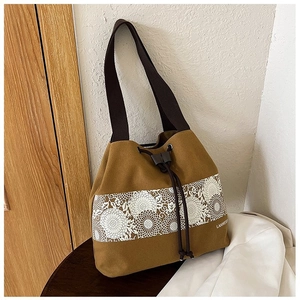 Detail of canvas bucket bag showing floral lace print, drawstring closure, and fabric strap