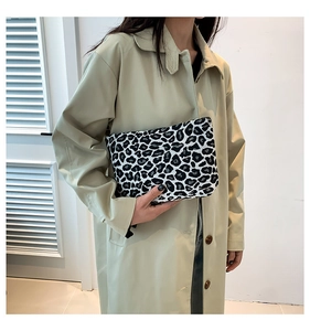 Detail shot of rectangular leopard print clutch bag held against a minimal background