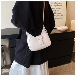 Detail view of white half-moon crossbody bag with elegant crocodile pattern and buckle