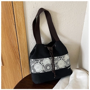 Detail view of black canvas bucket bag featuring floral embroidery and drawstring closure
