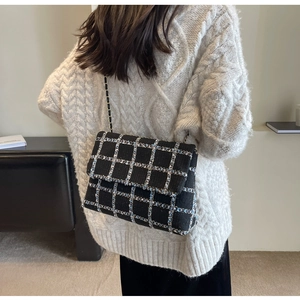 Gros plan d'un sac à bandoulière en tweed à carreaux noir et blanc avec chaîne