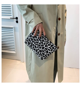 Detailed view of leopard print clutch bag with black and white textured fabric and zipper