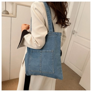 Detail of classic blue denim tote bag featuring dual front pockets and shoulder straps