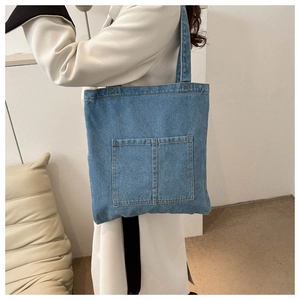 Detailed close-up of blue denim tote bag featuring dual front pockets and stitched texture