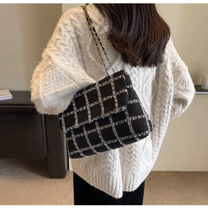 Texture détaillée du sac à bandoulière en tweed noir avec chaîne dorée et motif tissé