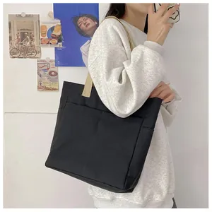 Vue détaillée du sac cabas en toile noire avec plusieurs poches de rangement avant