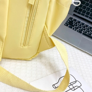 Dettaglio dello zaino in nylon giallo chiaro con tracolla rinforzata e cerniera in resina