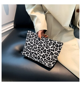 Close-up of black and white leopard print woven handbag with a metal zipper closure