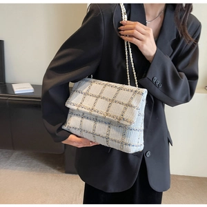 Détail de la texture en tweed bleu clair et de la bandoulière en chaîne dorée du sac