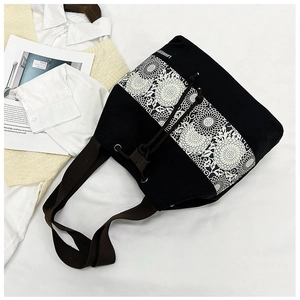 Detail view of black canvas bucket bag featuring floral lace trim and drawstring closure