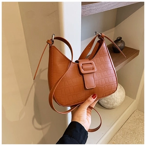 Close-up of caramel brown faux crocodile leather shoulder bag with buckle detail