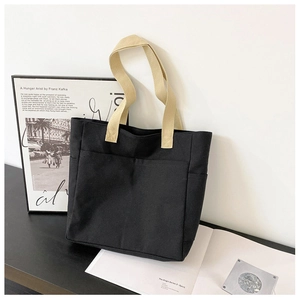 Détail du sac cabas en toile noire avec anses contrastées et grandes poches frontales