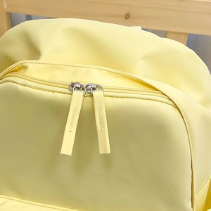 Dettaglio di uno zaino giallo resistente all'acqua con doppie cerniere e texture del tessuto