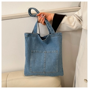 Minimalist light blue denim tote bag with dual front pockets and adjustable shoulder strap
