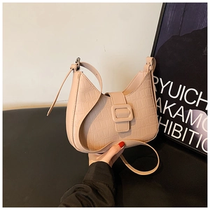 Detail of pink half-moon bag with crocodile pattern and stylish leather buckle strap