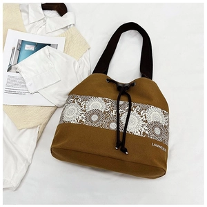 Detail view of khaki canvas drawstring bucket bag with white floral lace embroidery