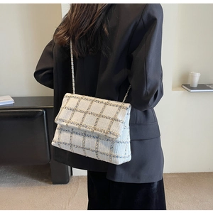 Détail du sac à rabat en tweed à carreaux bleu et or avec bandoulière chaîne dorée