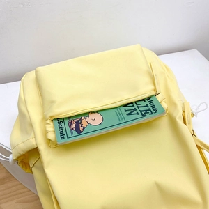 Dettaglio dello zaino in nylon giallo chiaro con tasca frontale e cordino bianco