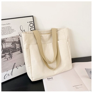 Détail d'un sac cabas en toile avec poches latérales et anses en ruban de couleur kaki