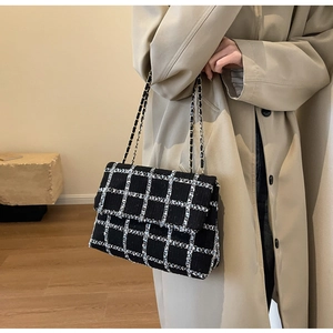 Gros plan du motif en tweed noir et blanc et de la bandoulière en chaîne dorée