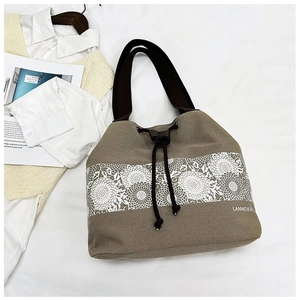 Detail of khaki canvas bucket bag featuring white lace floral patterns and drawstring closure