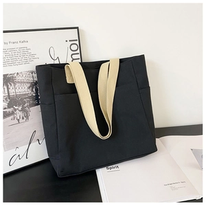 Gros plan du sac cabas en toile noire avec des poignées contrastées de couleur crème